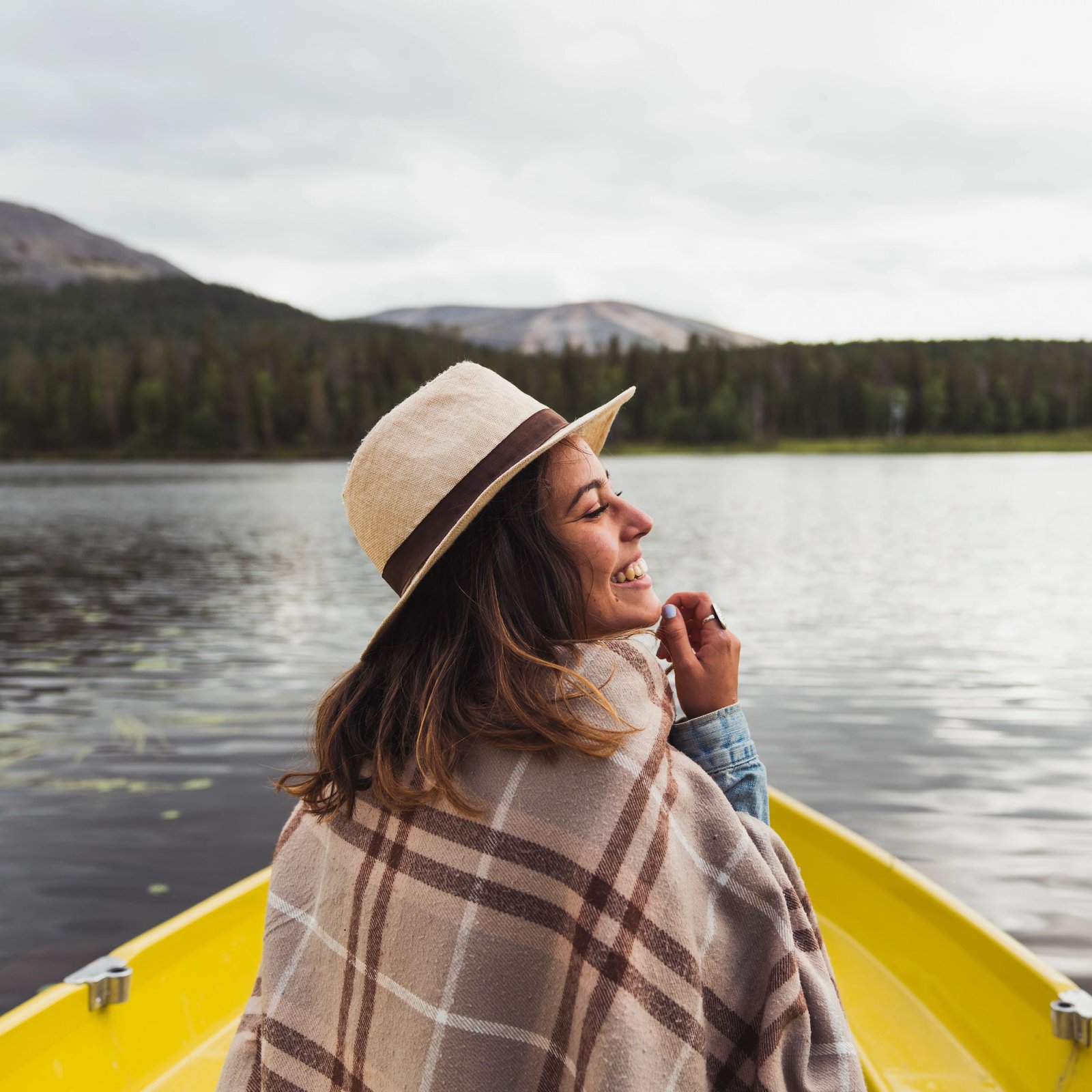 A happy woman wearing a hat on a boat on a lake in Finland